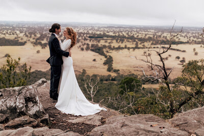 Bride and Groom standing on a cliff top looking out at the view.
