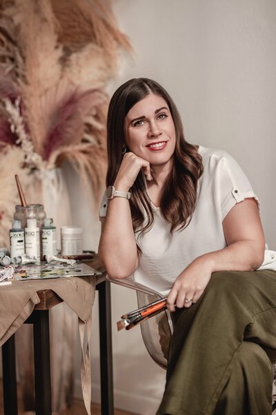 A photo of Debbie, holding several paintbrushes in her hand