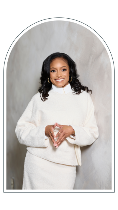  Dr. London Murray smiling confidently while wearing an elegant white outfit, standing against a soft neutral background.