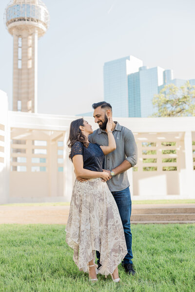 couple standing at JFK Memorial in downtown Dallas with  Reunion Tower in the background