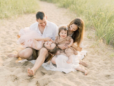 family of four playing during a beach family session By Carrie Pellerin