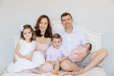 A family sitting on a bed together looking at a newborn baby