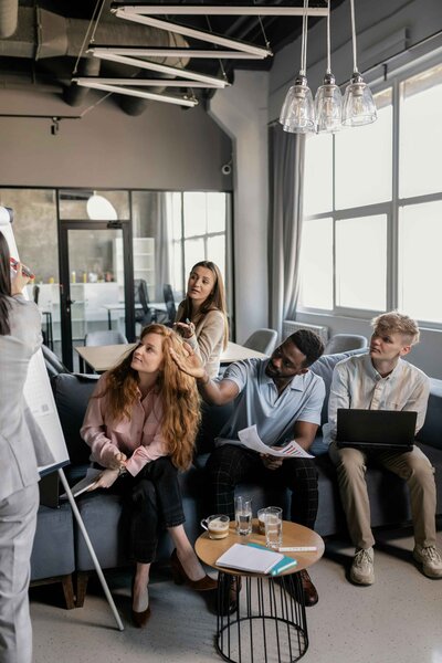 PPC advertising experts in an office meeting, focused on their boss while working on laptops, demonstrating teamwork and attention to detail in managing campaigns.