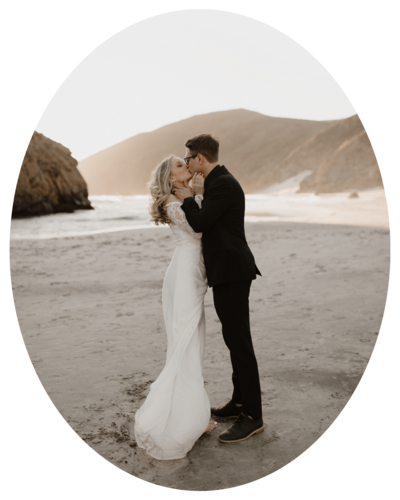bride and groom standing and kissing in front of beach mountains