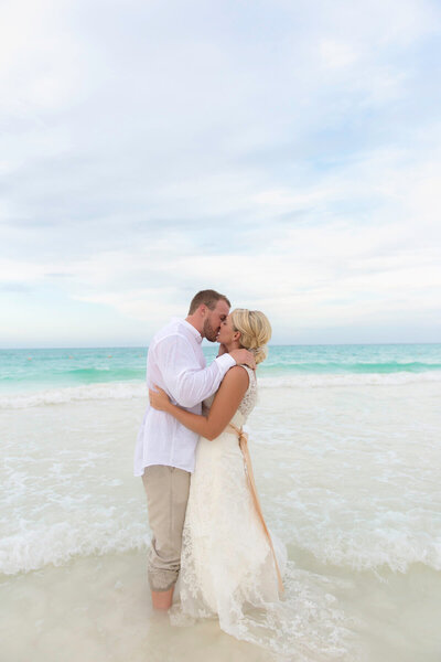 Newly married husband and wife kiss in the water at the beach