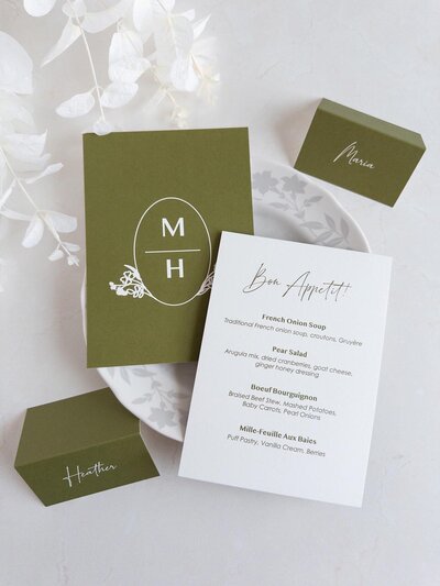 Custom event branding flat lay including a custom modern crest, personalized menus and matching place cards