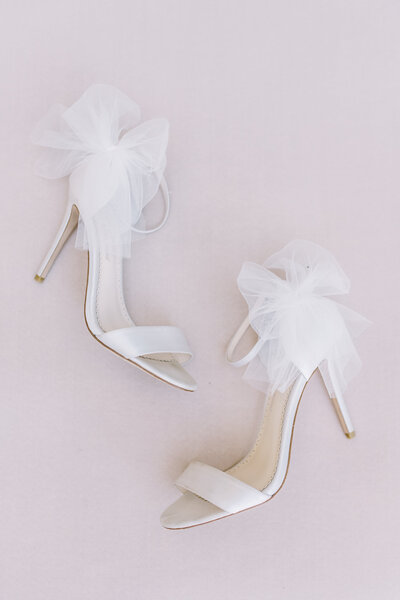 Wedding shoes with bows on them laying on the floor