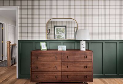 Updated bedroom space with custom green wainscoting, patterned wallpaper, and a wood dresser with contemporary styling.