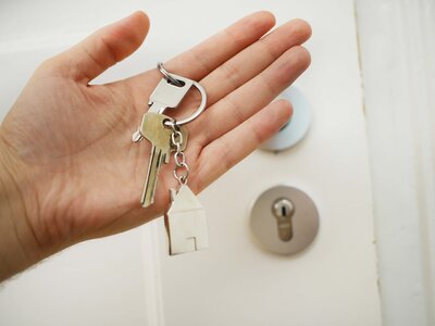 Close up of a person's hand holding a keychain with a house key