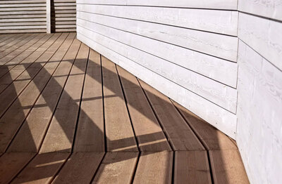 image of composite decking and white siding with railing shadows on the decking