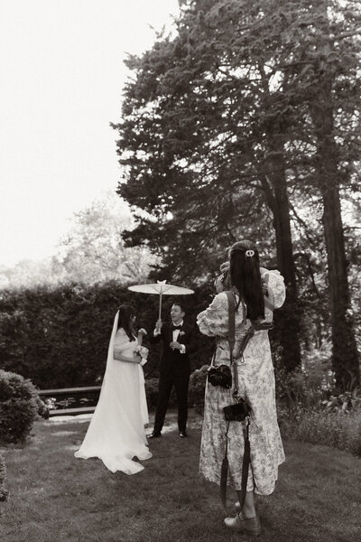 Bride and groom posing outdoors with an umbrella