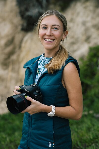 Jenn Whalen, a California elopement photographer, smiles with her camera.