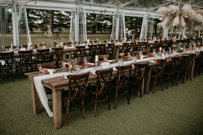 long wood tables, wood chairs in a clear tent