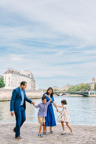 Playful family during a Paris family photoshoot on Île Saint-Louis in the city center, sharing joyful moments together.