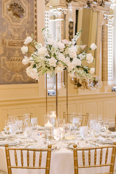 Elegant wedding reception centerpiece featuring lush floral arrangements with roses, greenery, and soft candlelight, designed by Leigh Florist.