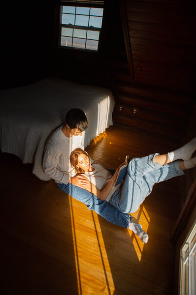 sunlight streaming through a winter window illuminating her face, captured in an intimate documentary style by Emily Ambie.