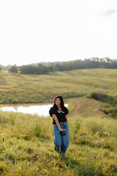 woman laughing while looking off in an open field with her camera