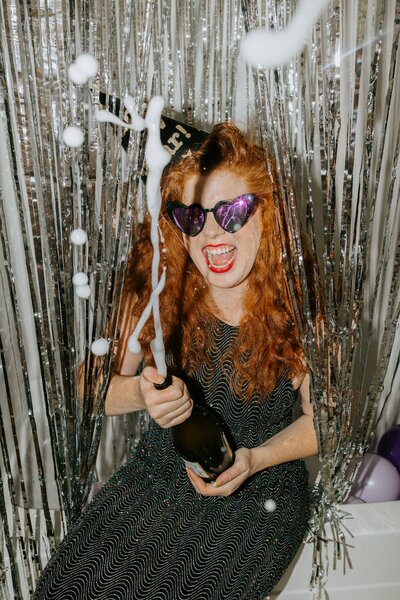 Leanna pops and sprays a bottle of champagne for a photoshoot.