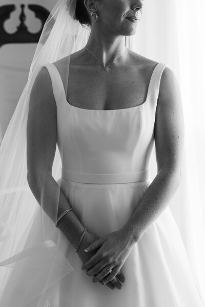 Bride in a detailed wedding dress looking out the window, serene moment captured in New York City by Hallie Noel Photography.