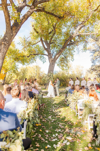 ​​Bride and groom holding hands during their ceremony at the Botanical Gardens in Cheyenne. Wyoming. 