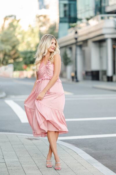 teen girl with blonde hair wearing a pink dress in the city