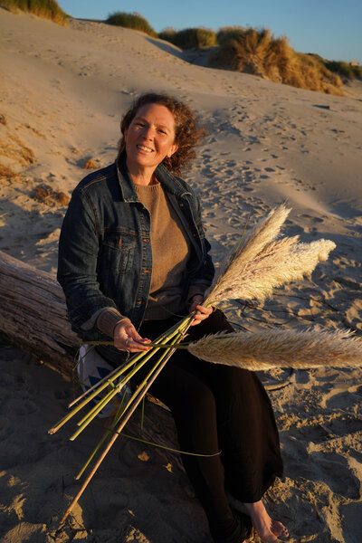 Smiling woman sitting on beach log