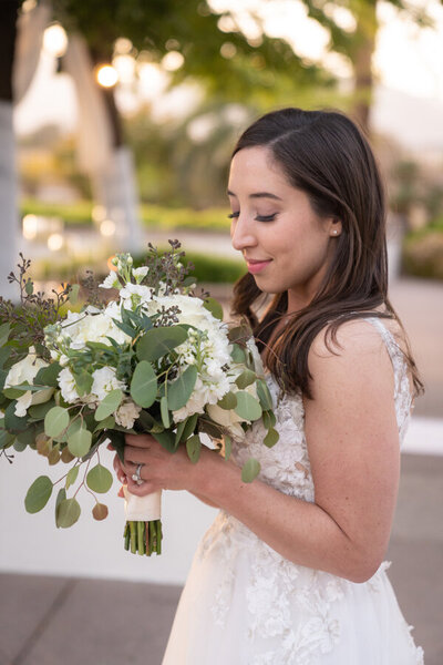 A bride holding a bouquet of white flowers, wearing her lace wedding dress