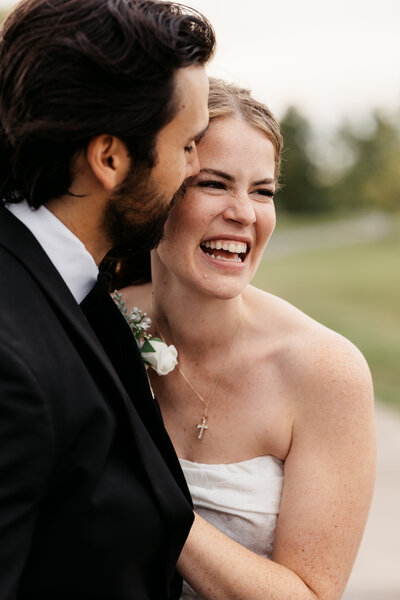 wedding couple snuggle together at a park