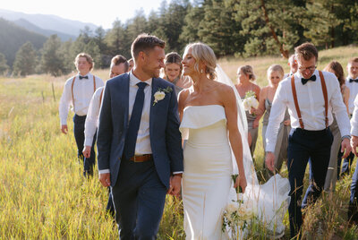 Bride and groom walk through field in evergreen Colorado