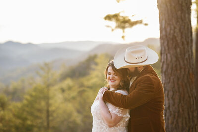 foothills elopement with groom in a cowboy hat holding his bride around the shoulders as she smiles while they elope to Gatlinburg in the Smoky Mountains