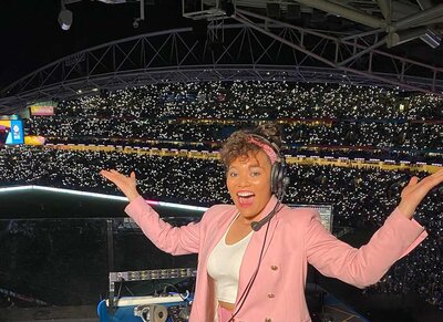 Excited female DJ with headset performing in a packed stadium during the FIFA Women’s World Cup 2023