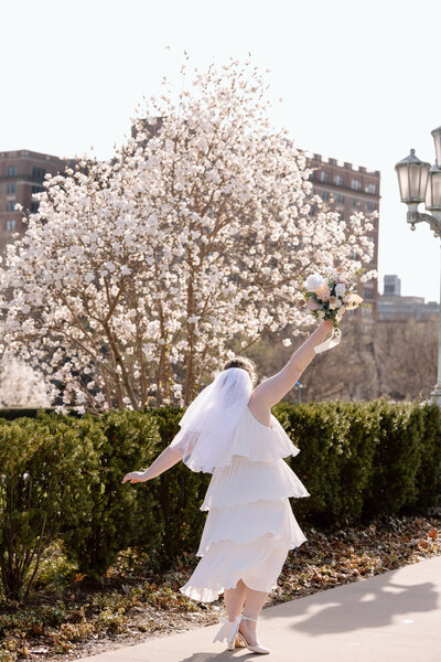 Bride twirling in front of blossoming trees in the spring.