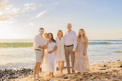 Drone maternity portrait featuring beautiful pregnancy portrait of woman in white dress laying on the sand