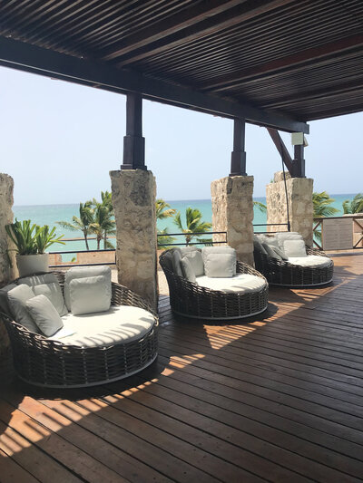 A picturesque wooden deck featuring white pillows, offering a stunning ocean view, ideal for a romantic destination wedding.