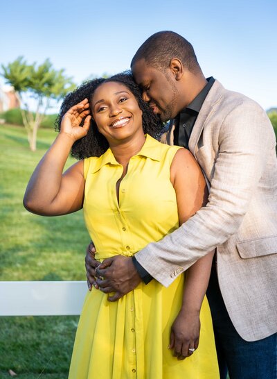 An African-American couple embrace near a white fence.