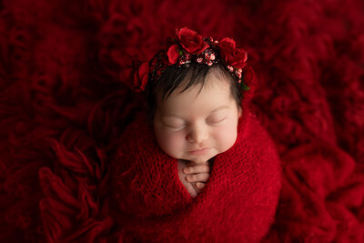 newborn baby wrapped in red. Roses on head