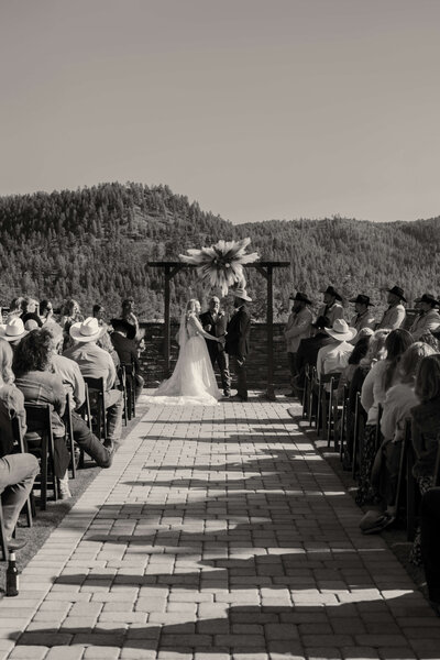 Black and white photo of bride and groom holding hands during Arizona outdoor ceremony.