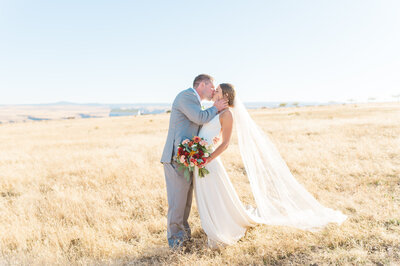 wedding portrait where bride and groom are kissing in a field at a private estate property in eastern washington 