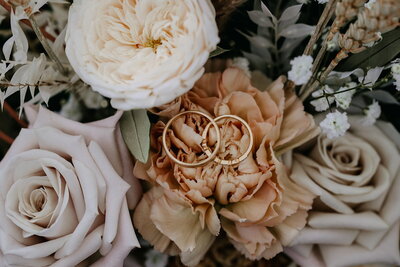 Witte roos, menta roos en chrysant waar een gouden ring op ligt