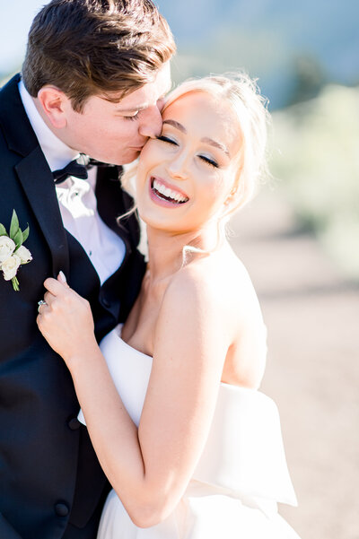 bride smiles as groom kisses her cheek