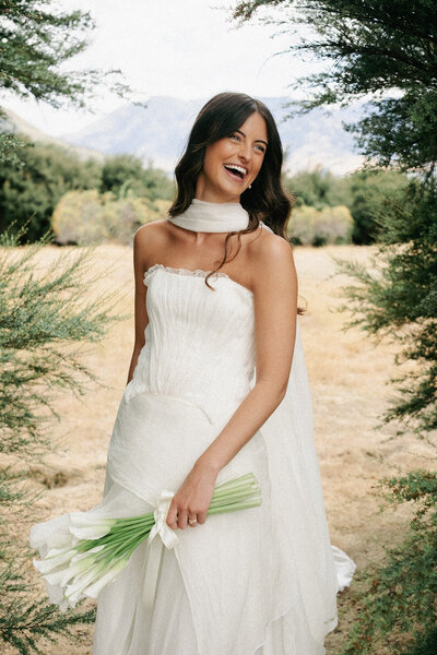 bride laughing on her wedding day in queenstown with hair and makeup