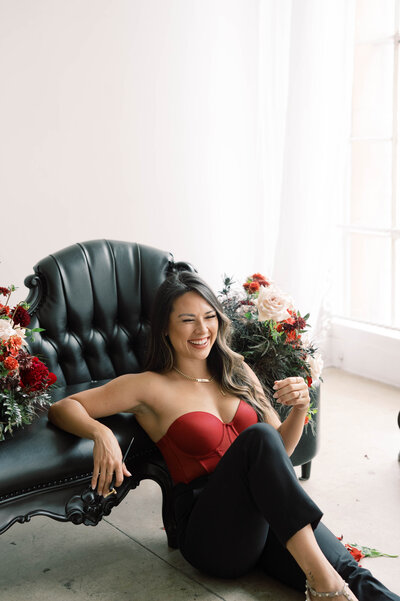 Los Angeles based calligraphy artist Cat Lauren sitting wearing a red top and black pants