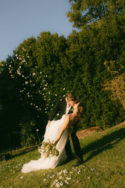 Motion blur photo with groom with glasses and a blue suit dipping bride