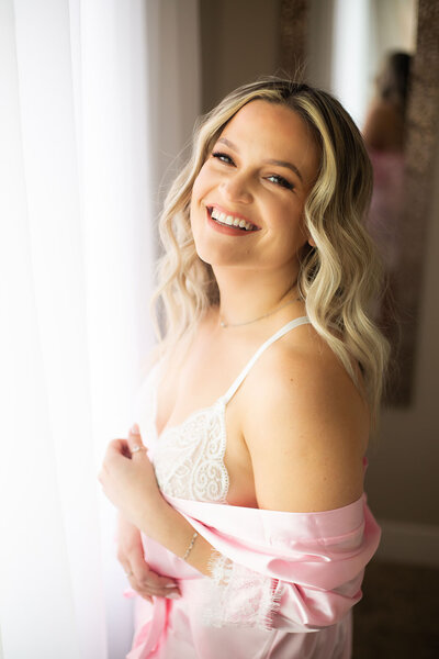 Latina woman with blonde hair smiling at the camera during her boudoir shoot