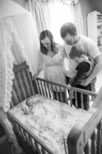 Parents and brother looking down at newborn baby | Newborn Maine Photographer