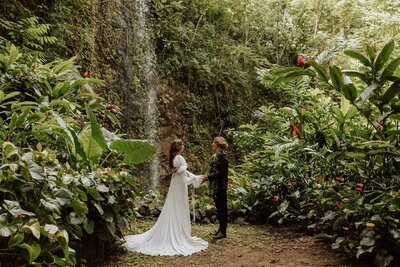 bride and groom saying vows in a jungle with a waterfall
