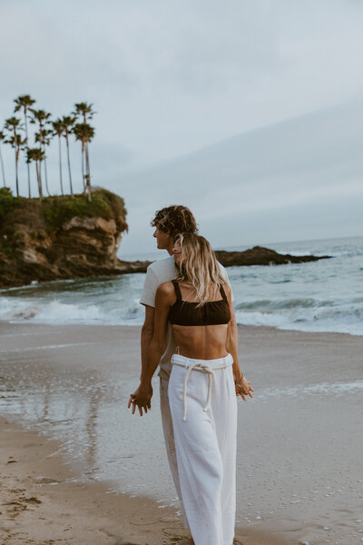 Engagement session with man and woman on beach with palm trees