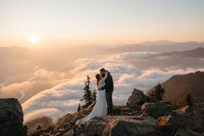 Bride and groom kissing during a hiking elopement on top of a mountain at sunset