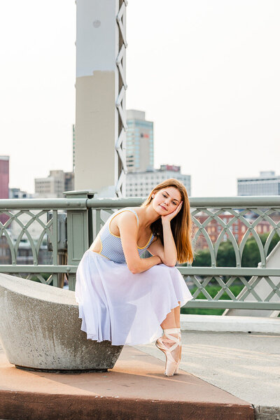Girl sitting on a bench on a bridge in ballet attire