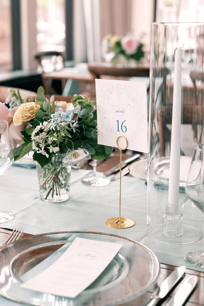 floral table number and menu for a pastel wedding at Moonlight Basin, styled with soft greenery, blush and blue florals, and gold accents on the tablescape.